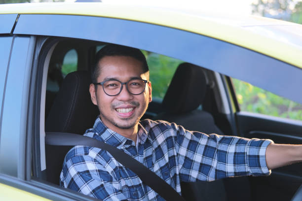 Asian man smiling to camera while driving his car